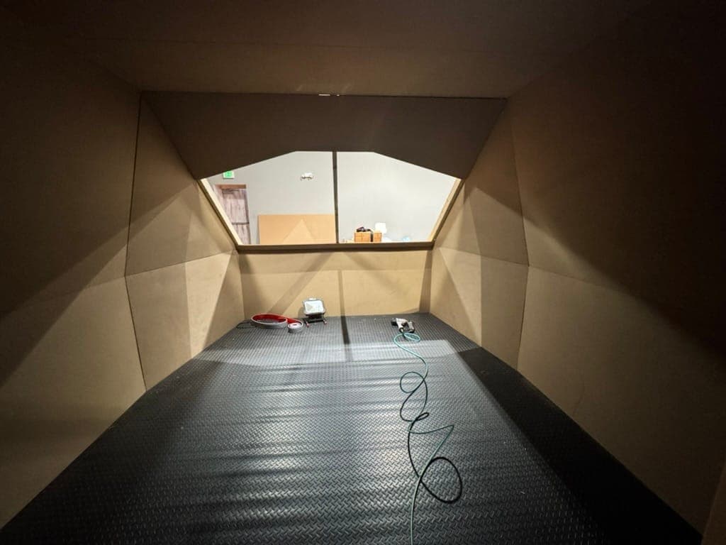 Inside the raw cockpit shell before finish, with the window opening cut and the floor laid