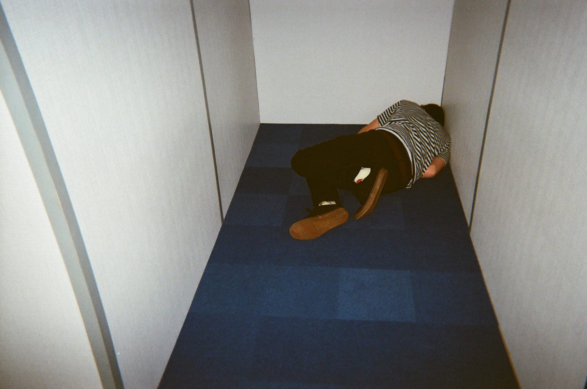 A crew member sprawled out and exhausted on the floor of a narrow set hallway