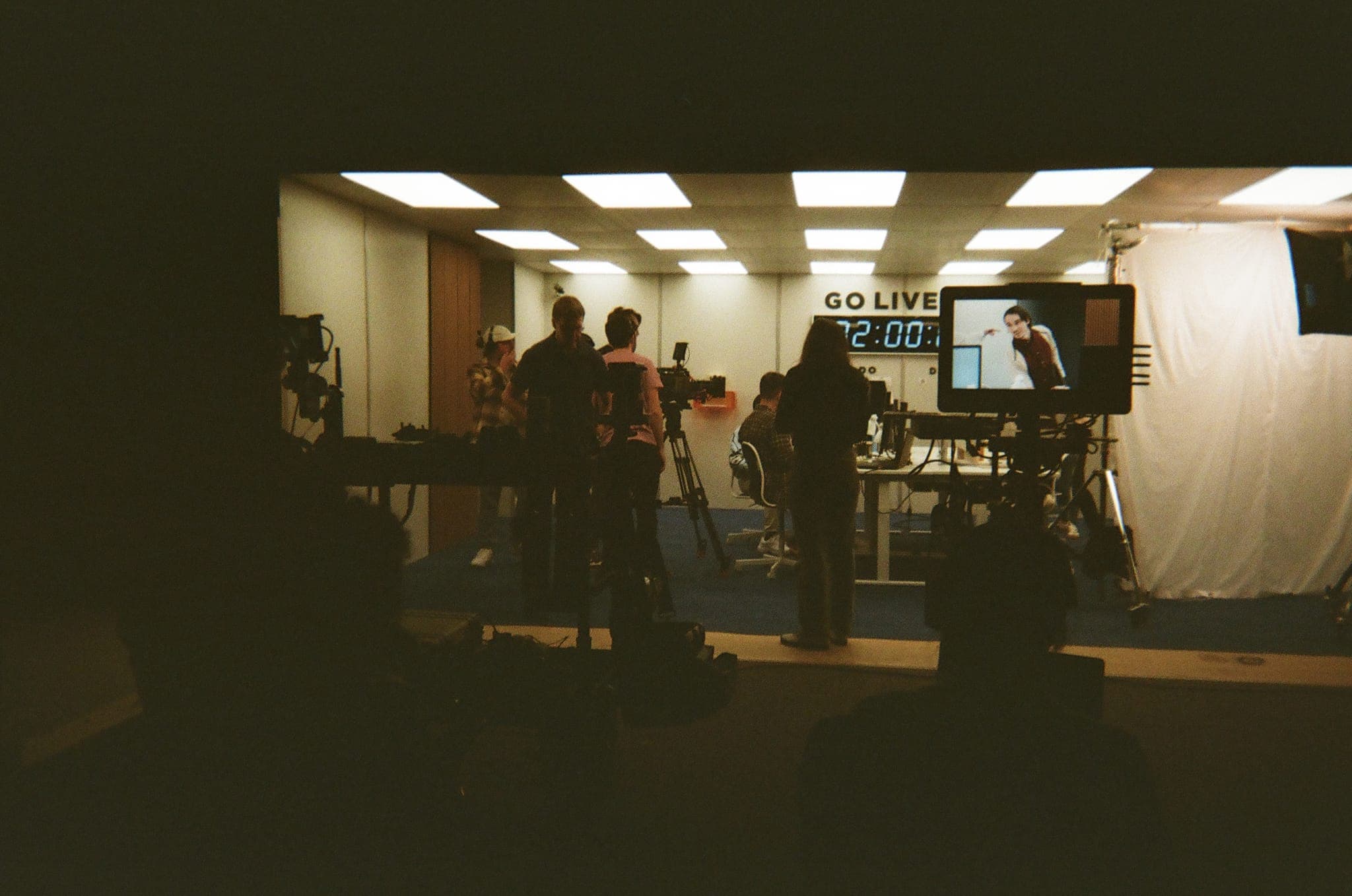 Crew and camera silhouetted in front of a lit GO LIVE countdown set